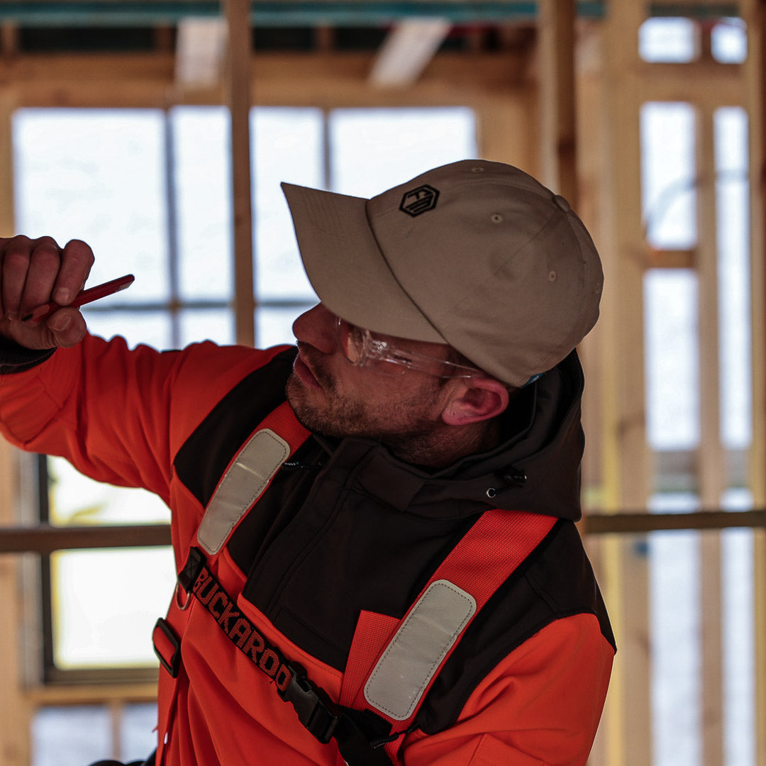 Construction worker adjusting his tools while wearing a hi-vis harness and beige cap from Form Workwear
