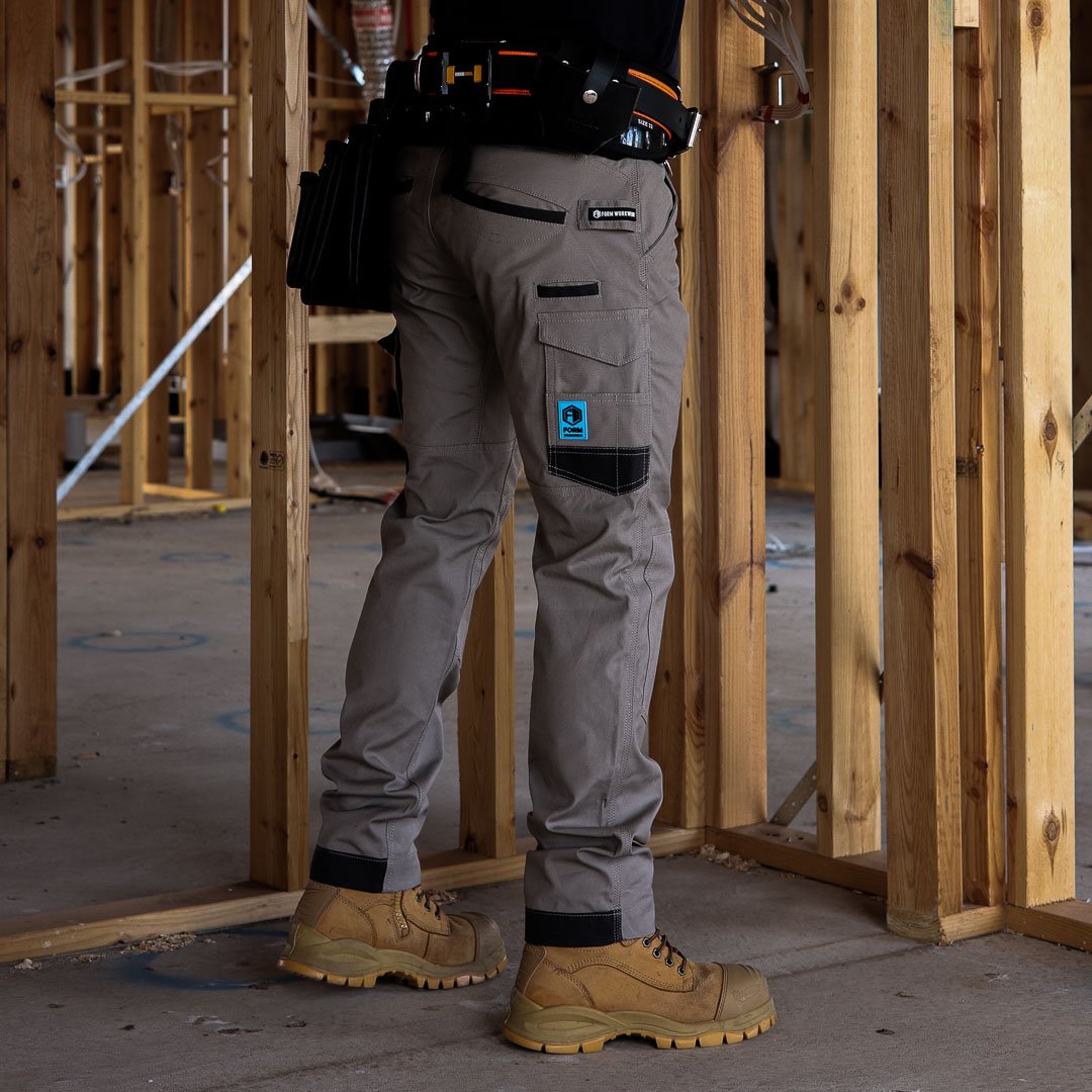 Tradie wearing FB2 khaki work pants on construction site with tool belt and boots