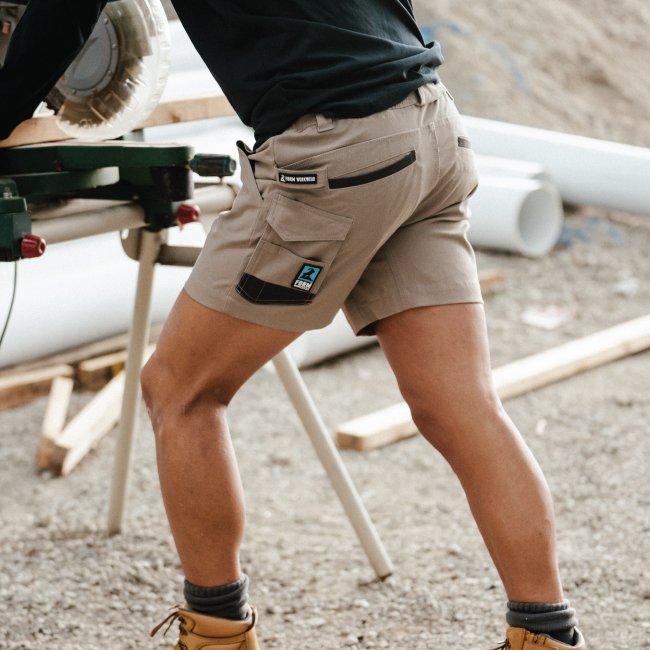 carpenter cutting wood using a table saw wearing mens work shorts