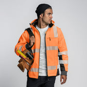 Tradesman wearing Form Workwear FT6 hi-vis orange jacket holding a tool belt