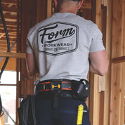 Tradie wearing grey Form Workwear t-shirt with bold back logo on a construction site