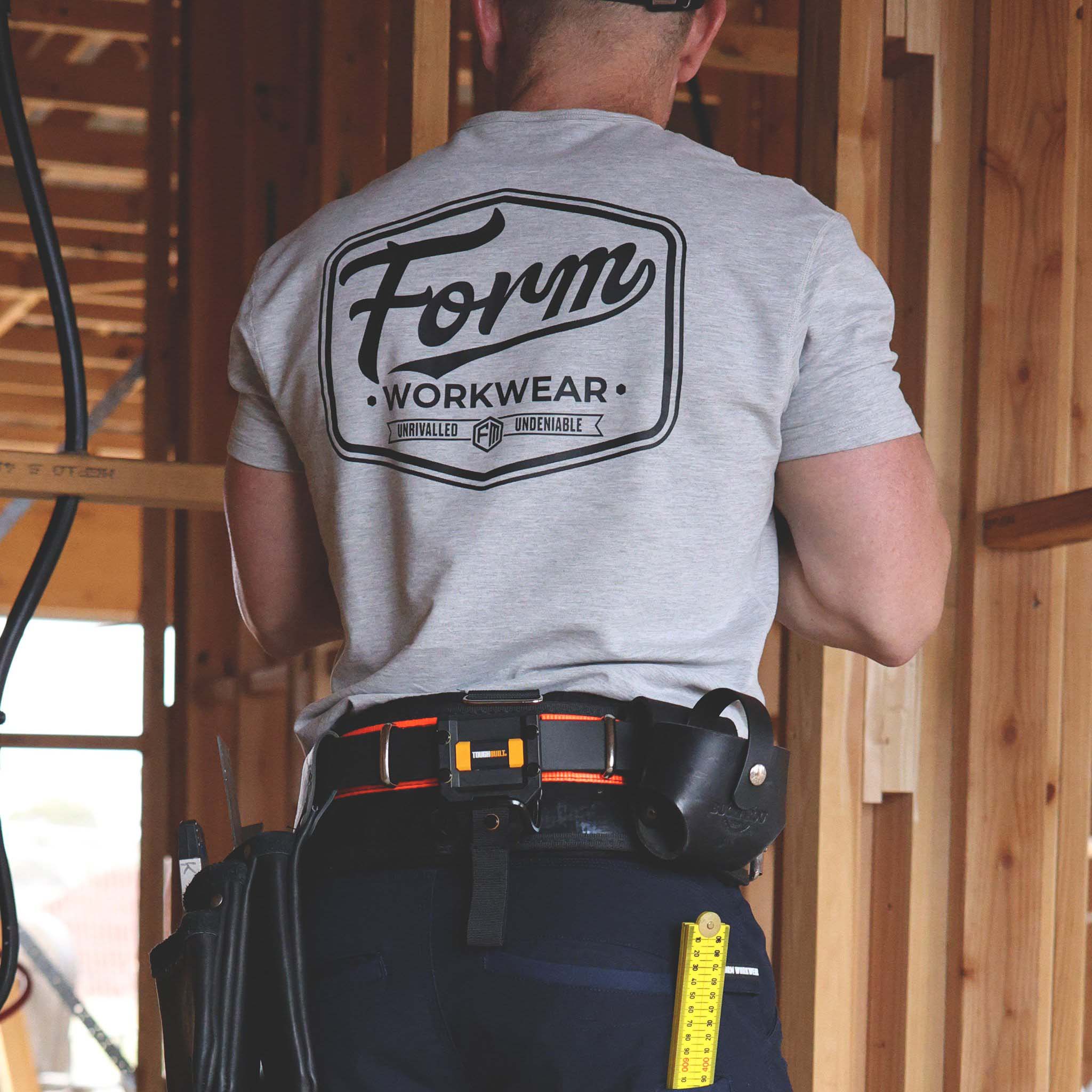 Tradie wearing grey Form Workwear t-shirt with bold back logo on a construction site