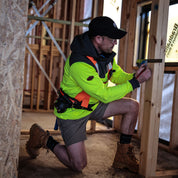 Tradesman wearing hi-vis yellow hoodie measuring on-site woodwork