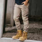 Tradesman wearing khaki Form Workwear pants and tan work boots standing on a construction site