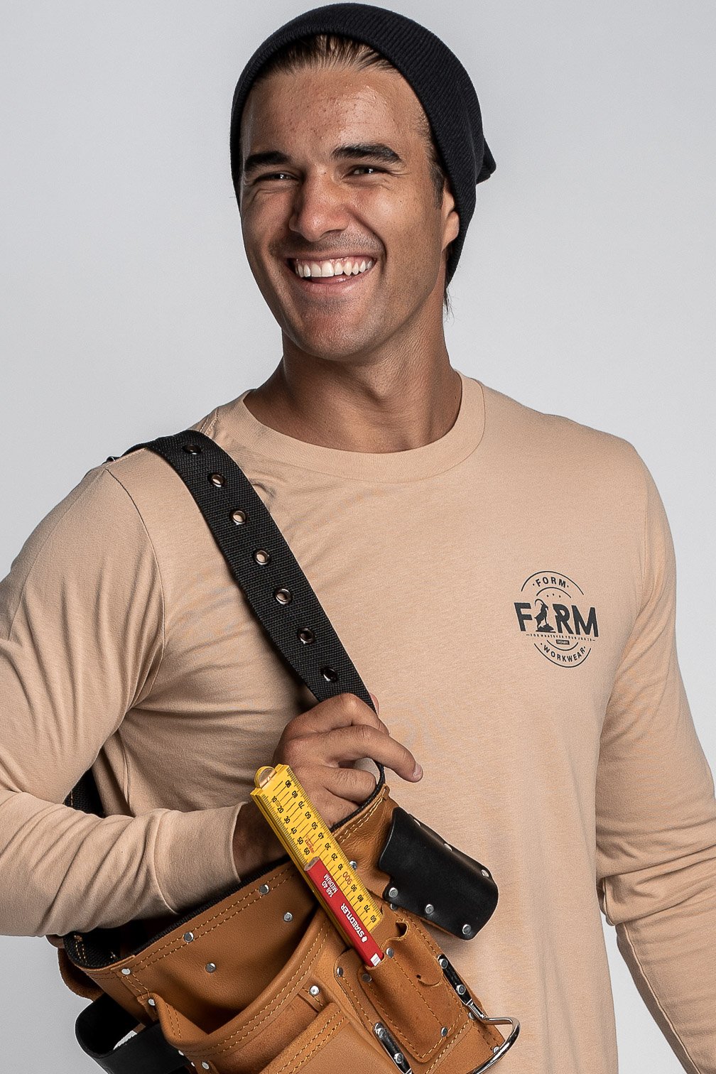 Model smiling while wearing a beige Form Workwear logo t-shirt